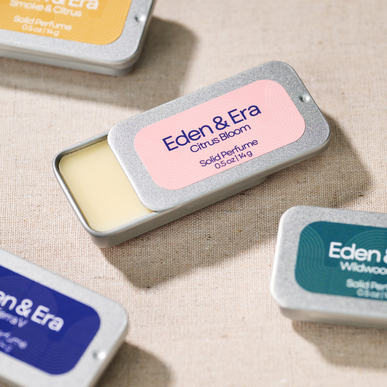 Eden & Era solid perfume tins arranged on linen