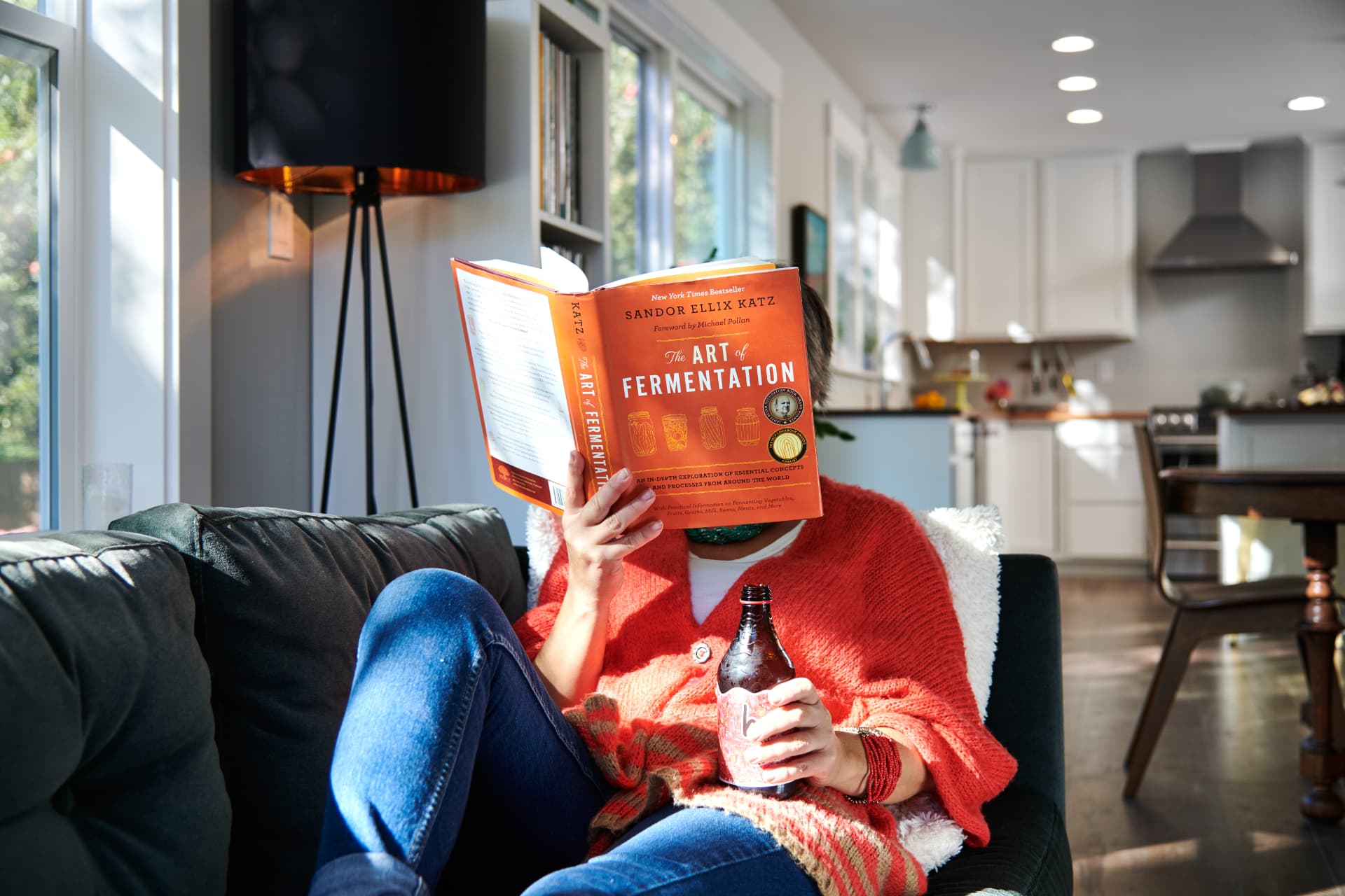 Reading The Art of Fermentation with a Humm bottle on a sunny couch